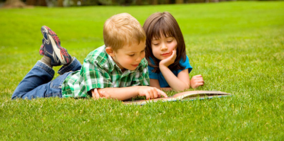 Brother and sister reading on the grass